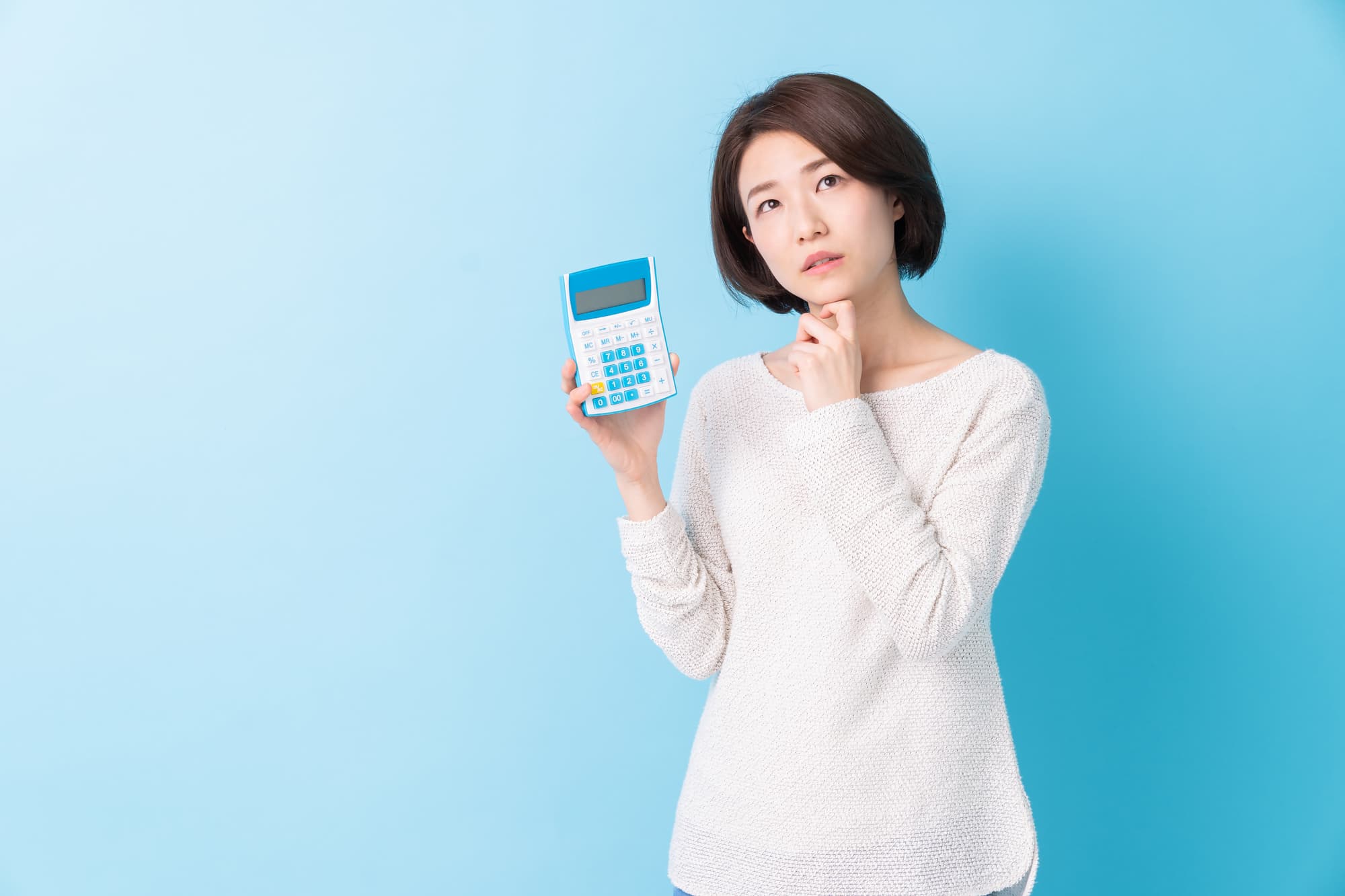 セラミック歯の値段はいくらか電卓を持って考える女性