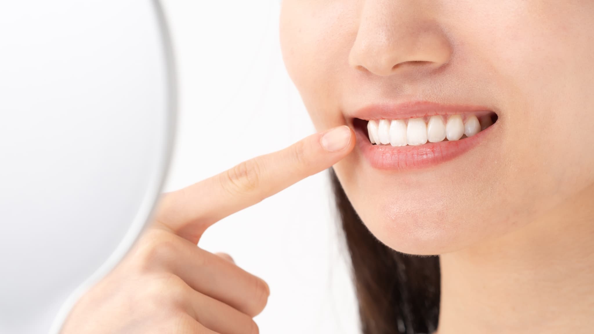 歯の色を鏡でチェックする女性