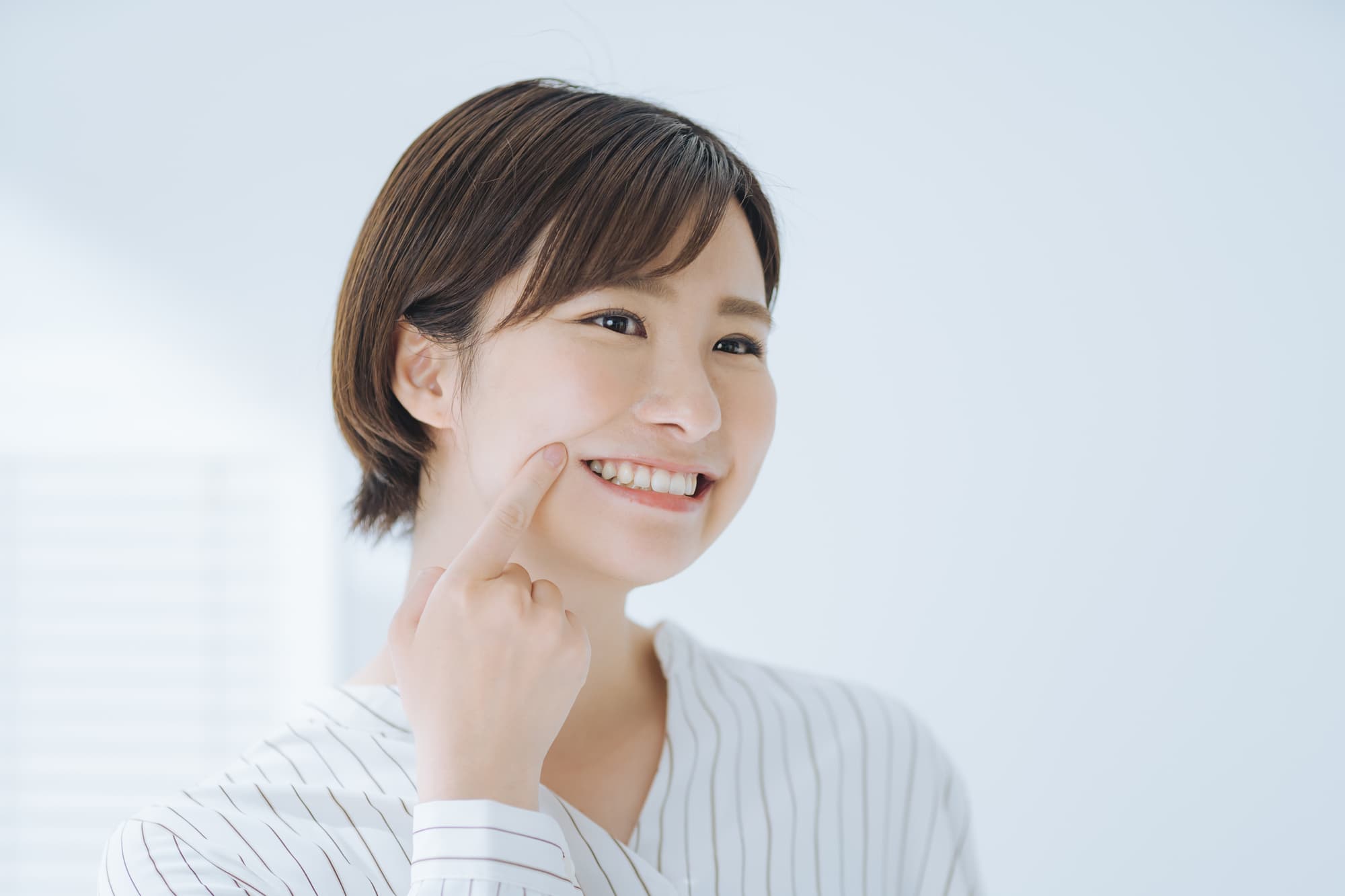 インプラントにした奥歯を指さす女性