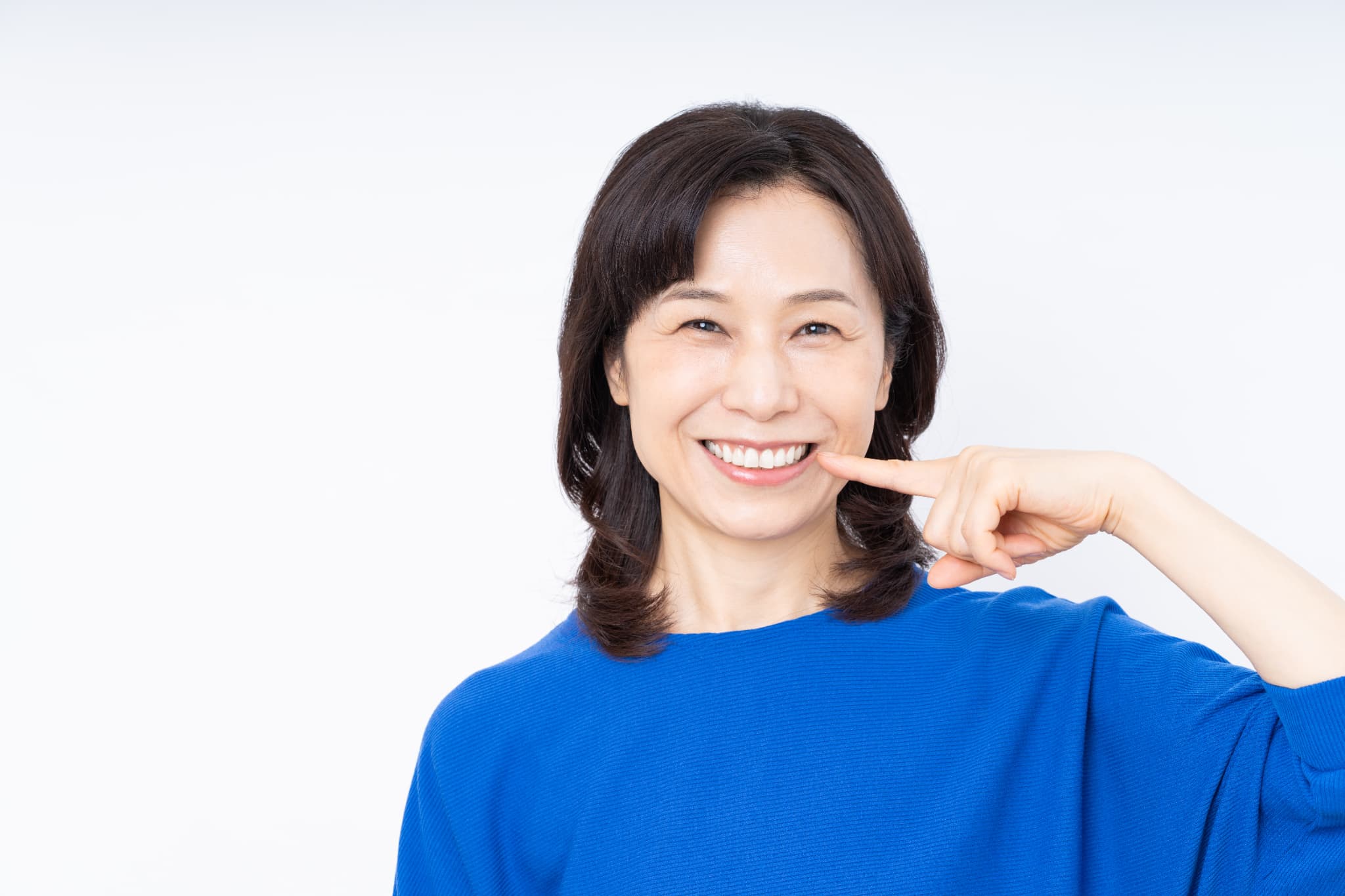 ブリッジ治療をした歯を指さして笑顔を見せる女性